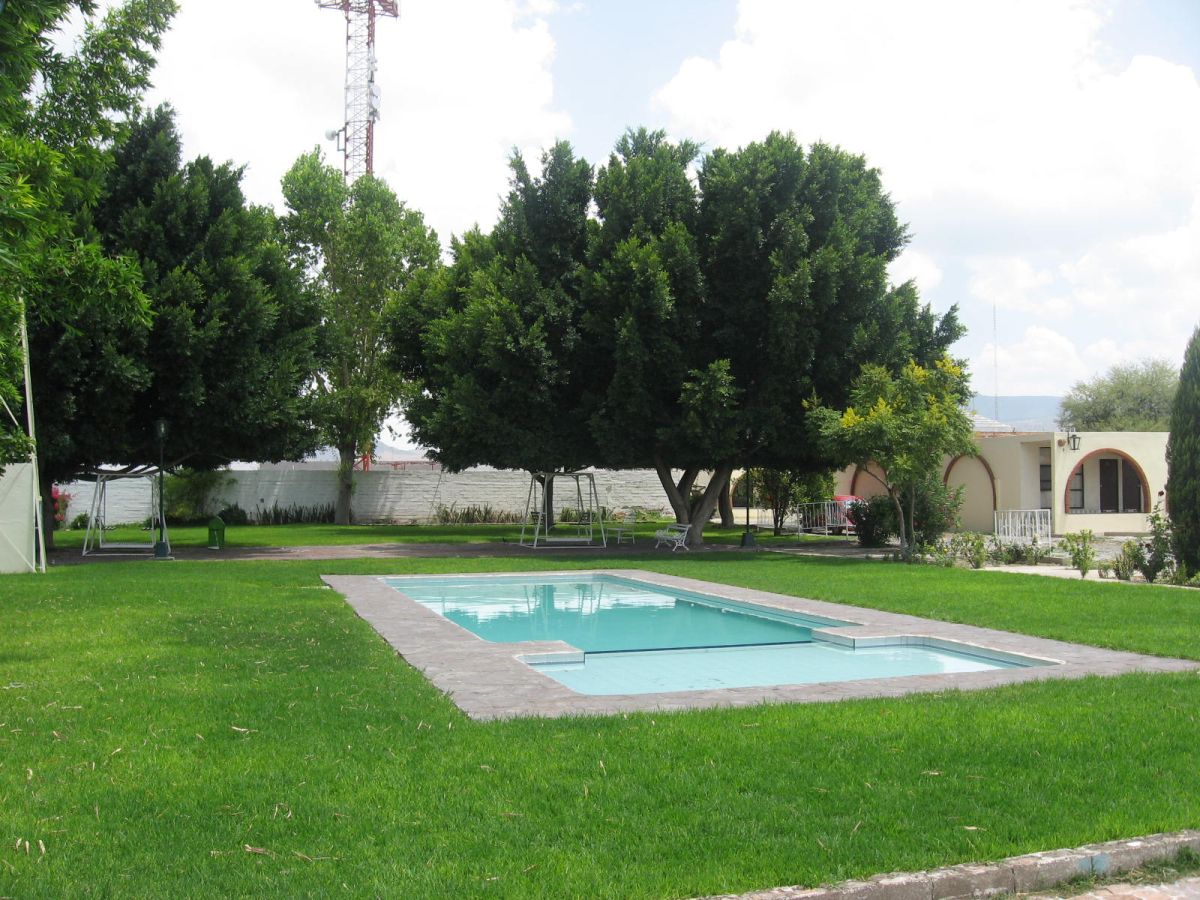 Alberca al aire libre rodeada de árboles y jardines en el Hotel Colonial