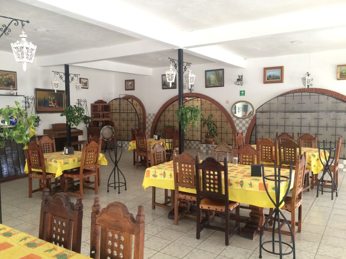 Restaurante del Hotel Colonial con mesas de manteles amarillos y arcos de ladrillo
